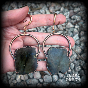This pair of gorgeous earrings features large shimmering labradorite slices with rustic ornate copper plate detail, weighing approx 22 grams a piece, not too heavy, and measuring just on 9cms from tip to tip.

These earrings have been made on 6 gauge (4mm) surgical steel full curl hooks, to be worn in stretched lobes.