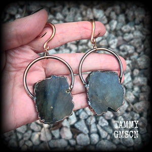 This pair of gorgeous earrings features large shimmering labradorite slices with rustic ornate copper plate detail, weighing approx 22 grams a piece, not too heavy, and measuring just on 9cms from tip to tip.

These earrings have been made on 6 gauge (4mm) surgical steel full curl hooks, to be worn in stretched lobes.