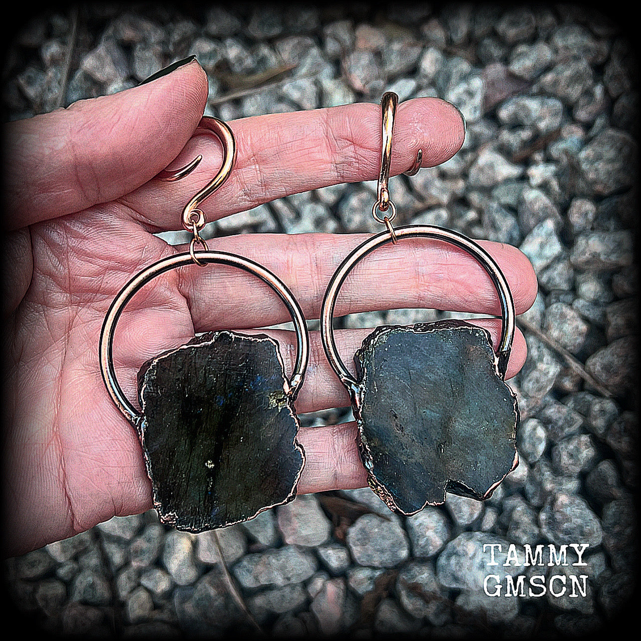 This pair of gorgeous earrings features large shimmering labradorite slices with rustic ornate copper plate detail, weighing approx 22 grams a piece, not too heavy, and measuring just on 9cms from tip to tip.

These earrings have been made on 6 gauge (4mm) surgical steel full curl hooks, to be worn in stretched lobes.
