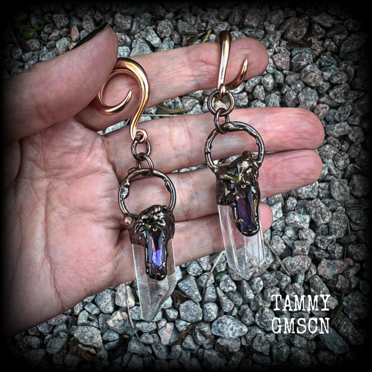 These clear quartz and amethyst gauged earrings are simply gorgeous!!
Featuring gorgeous amethyst stones sitting on front of chunky quartz pillars in an antique copper setting, these gauged earrings measure just on 9.5cms from tip to tip, and weigh approx 25 grams each.
This pair has been made on 6 gauge (4mm) surgical steel full curl hooks, suitable to be worn in stretched lobes.