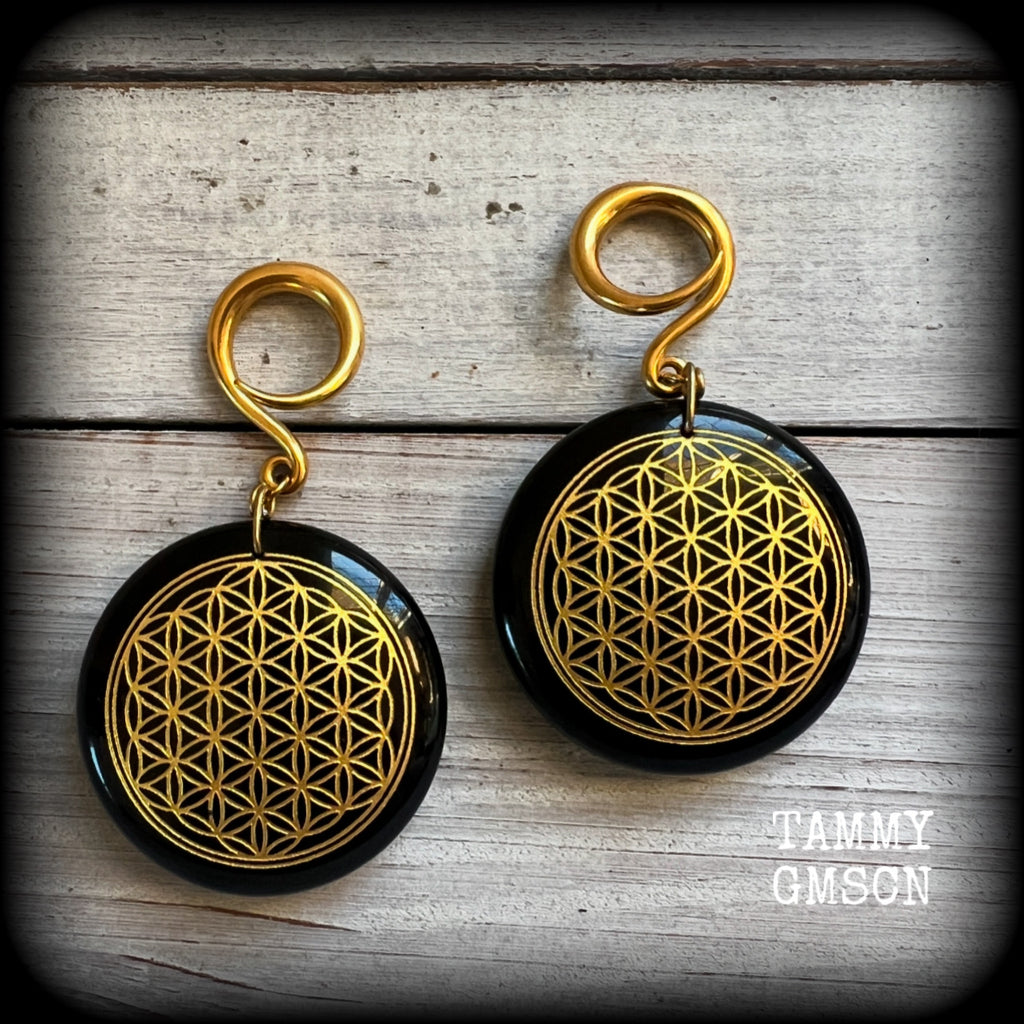 These beautiful ear hangers feature gorgeous pitch black obsidian gemstones etched with a beautiful gold flower of life motif, measuring just over 7cms from tip to tip, and weighing approx 24 grams each.

This pair has been made on 6 gauge (4mm) surgical steel full curl hooks, to be worn in stretched lobes.