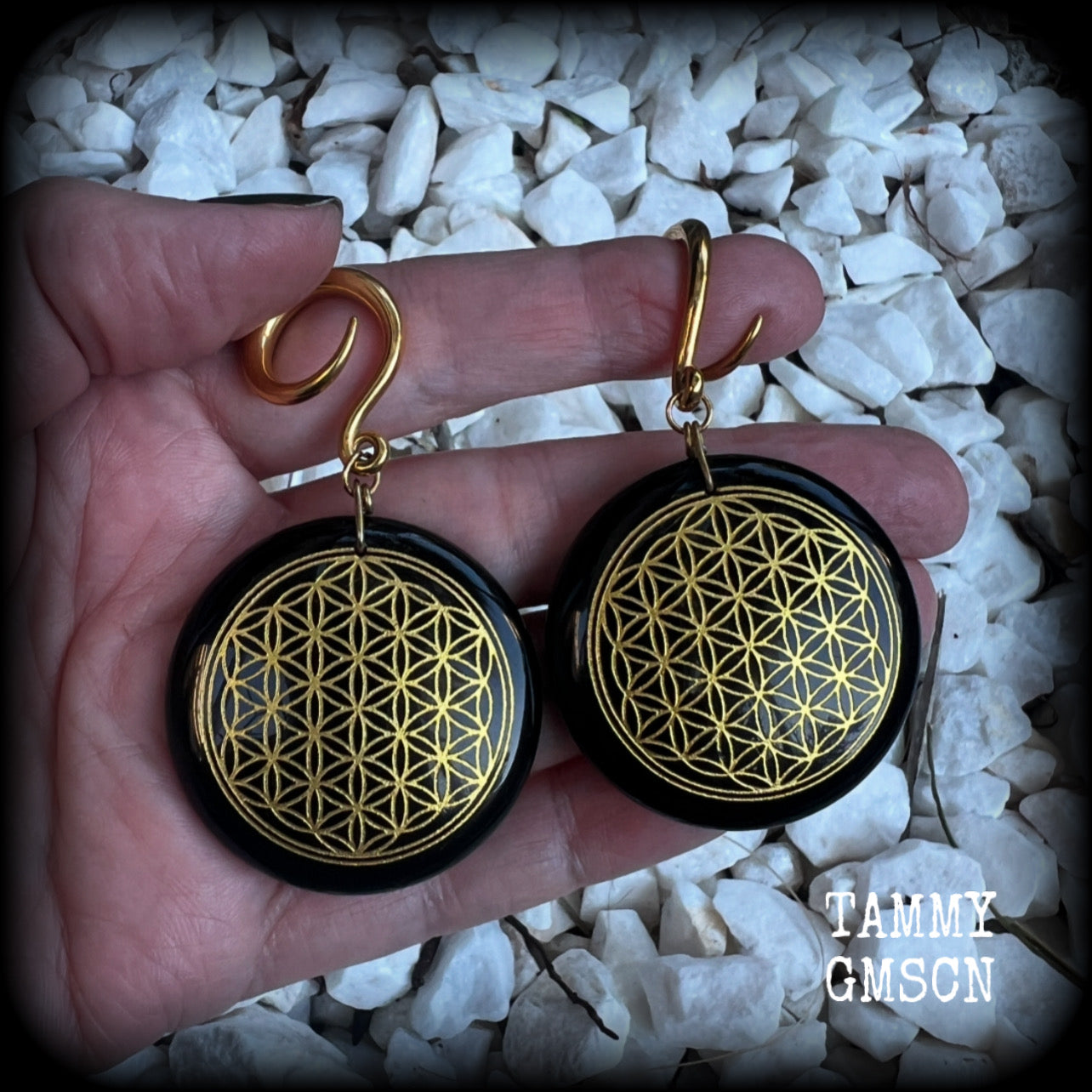 These beautiful ear hangers feature gorgeous pitch black obsidian gemstones etched with a beautiful gold flower of life motif, measuring just over 7cms from tip to tip, and weighing approx 24 grams each.

This pair has been made on 6 gauge (4mm) surgical steel full curl hooks, to be worn in stretched lobes.