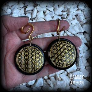 These beautiful ear hangers feature gorgeous pitch black obsidian gemstones etched with a beautiful gold flower of life motif, measuring just over 7cms from tip to tip, and weighing approx 24 grams each.

This pair has been made on 6 gauge (4mm) surgical steel full curl hooks, to be worn in stretched lobes.