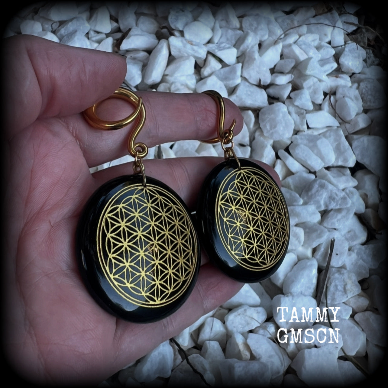 These beautiful ear hangers feature gorgeous pitch black obsidian gemstones etched with a beautiful gold flower of life motif, measuring just over 7cms from tip to tip, and weighing approx 24 grams each.

This pair has been made on 6 gauge (4mm) surgical steel full curl hooks, to be worn in stretched lobes.