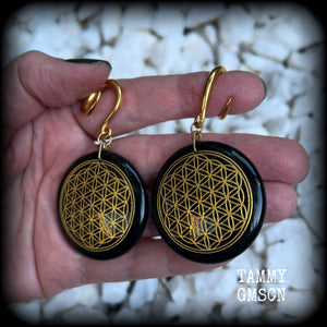These beautiful ear hangers feature gorgeous pitch black obsidian gemstones etched with a beautiful gold flower of life motif, measuring just over 7cms from tip to tip, and weighing approx 24 grams each.

This pair has been made on 6 gauge (4mm) surgical steel full curl hooks, to be worn in stretched lobes.