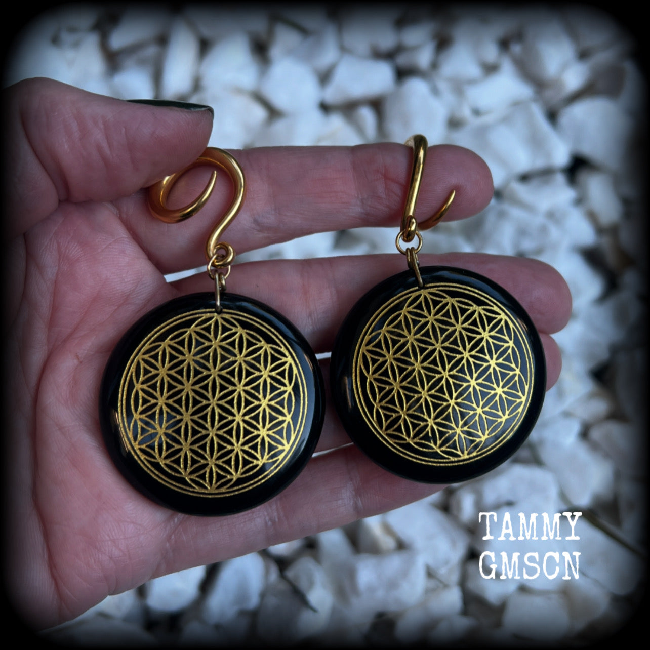 These beautiful ear hangers feature gorgeous pitch black obsidian gemstones etched with a beautiful gold flower of life motif, measuring just over 7cms from tip to tip, and weighing approx 24 grams each.

This pair has been made on 6 gauge (4mm) surgical steel full curl hooks, to be worn in stretched lobes.