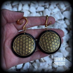 These beautiful ear hangers feature gorgeous pitch black obsidian gemstones etched with a beautiful gold flower of life motif, measuring just over 7cms from tip to tip, and weighing approx 24 grams each.

This pair has been made on 6 gauge (4mm) surgical steel full curl hooks, to be worn in stretched lobes.