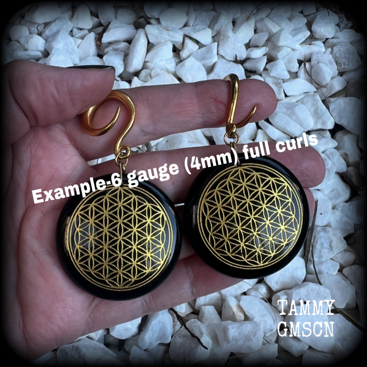 These beautiful ear hangers feature gorgeous pitch black obsidian gemstones etched with a beautiful gold flower of life motif, measuring just over 7cms from tip to tip, and weighing approx 24 grams each.

This pair has been made on 6 gauge (4mm) surgical steel full curl hooks, to be worn in stretched lobes.