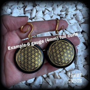These beautiful ear hangers feature gorgeous pitch black obsidian gemstones etched with a beautiful gold flower of life motif, measuring just over 7cms from tip to tip, and weighing approx 24 grams each.

This pair has been made on 6 gauge (4mm) surgical steel full curl hooks, to be worn in stretched lobes.