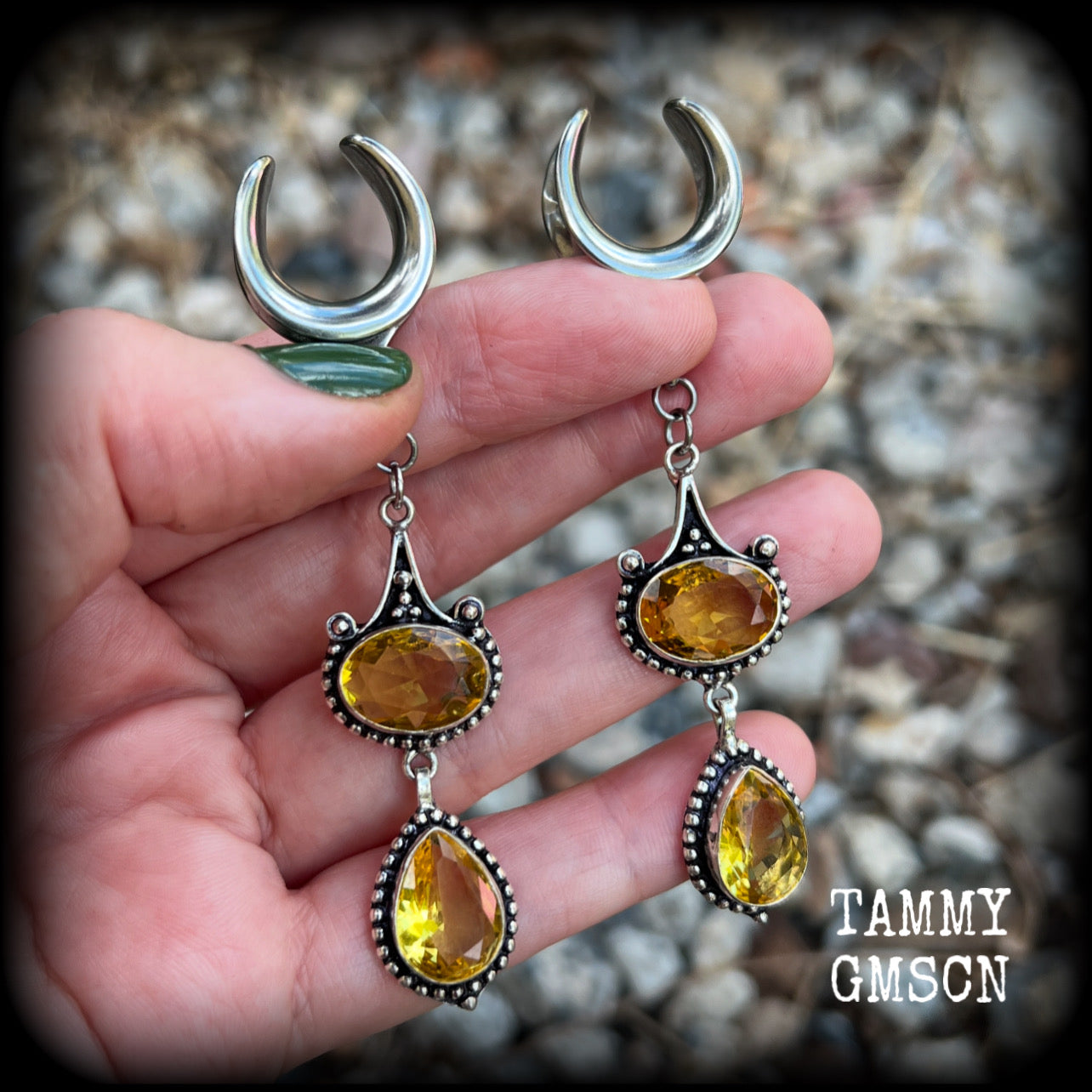 These earrings feature beautiful dangly yellow citrine gemstones in a gorgeous boho antique silver setting, 8.5cms from tip to tip, and weighing 11 grams each.
These earrings have been made on 5/8” gauge (16mm) surgical steel cradles.