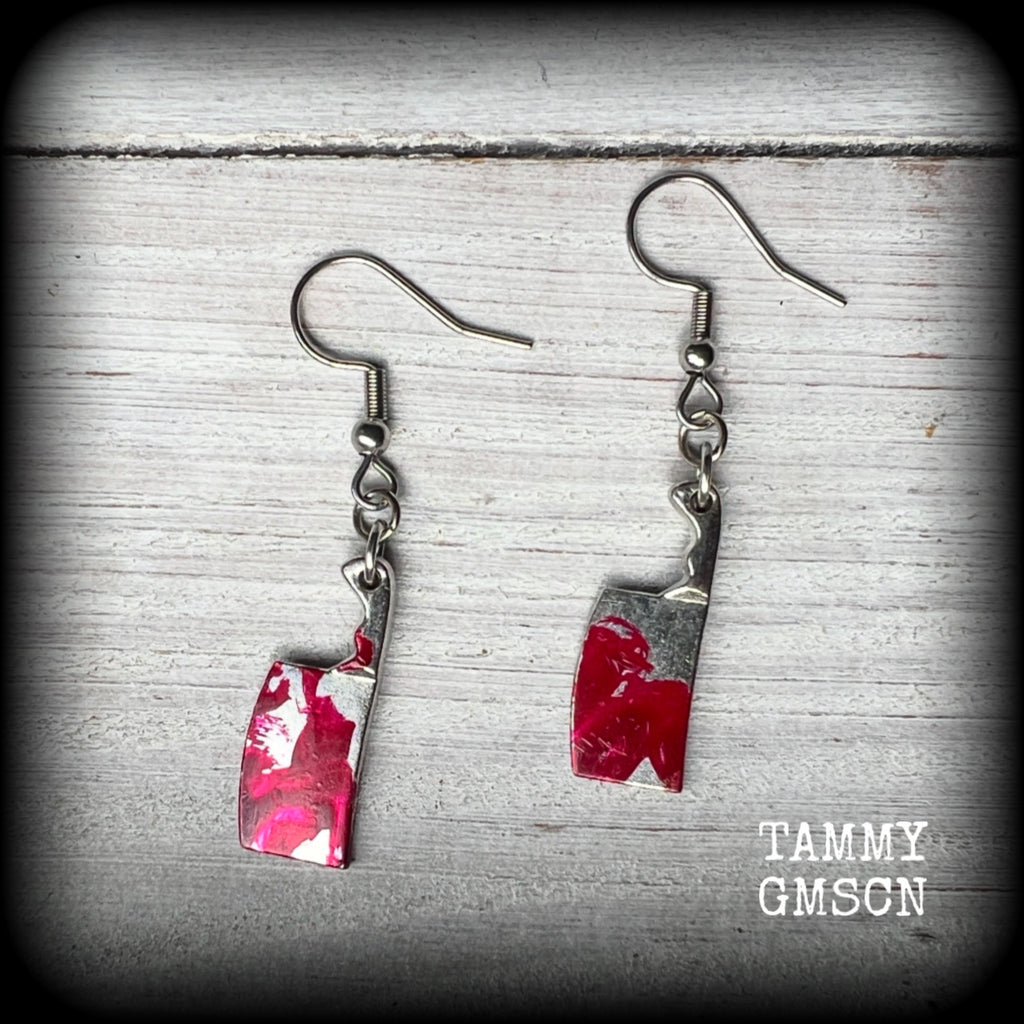 These awesome horror movie inspired earrings feature classic antique silver meat cleavers smeared with b l o o d. 
Measuring 5cms from tip to tip and weighing only 2 grams each, these are lovely and lightweight and nice and dangly.
