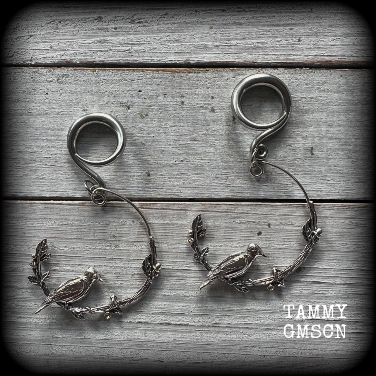 Featuring a gorgeous antique silver bird sitting on a branch wrapped with beautiful leafy vines, these delicate earrings measure just on 6.5 cms from tip to tip, and weigh approx 8 grams.
This pair have been made on 6 gauge (4mm) stainless steel full curl hooks, suitable for stretched lobes.