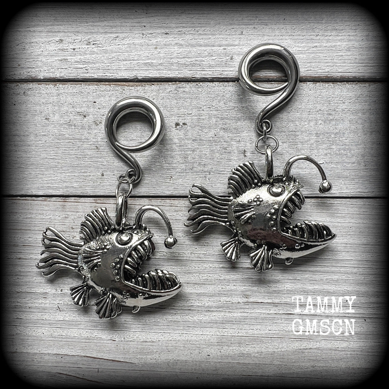 These gauged earrings are awesome!! Featuring dangly antique silver angler fish complete with a mouth full of sharp teeth, these earrings weigh in at 32 grams a piece, and measure just on 7.5cms from tip to tip.
This pair has been made on 2 gauge (6mm) surgicalsteel full curl hooks, to be worn in stretched lobes.