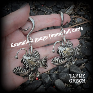 These gauged earrings are awesome!! Featuring dangly antique silver angler fish complete with a mouth full of sharp teeth, these earrings weigh in at 32 grams a piece, and measure just on 7.5cms from tip to tip.
This pair has been made on 2 gauge (6mm) surgicalsteel full curl hooks, to be worn in stretched lobes.