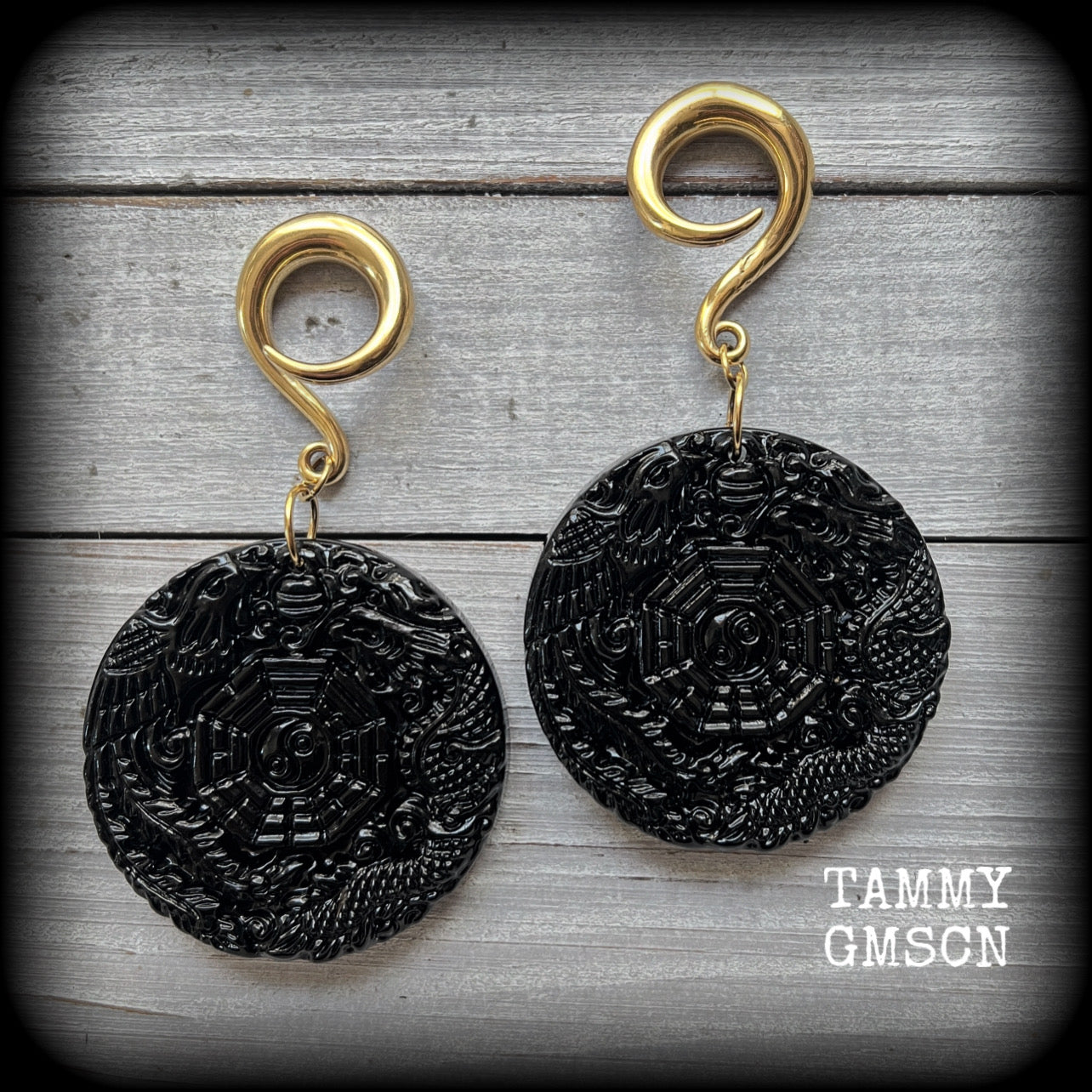 These gorgeous gauged earrings feature carved black obsidian pendants, showing a phoenix and dragon encircling the I-Ching hexagram.
These earrings weigh approx. 35 grams each and measuring just under 9cms from tip to tip.
This pair has been made with 2 gauge (6mm) surgical steel full curls, suitable for stretched lobes.