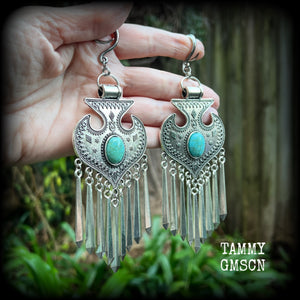 Inspired by Hathor, these unique ethnic inspired gauged earrings feature gorgeous antique silver pendants with beautiful turquoise stones.
These are gorgeous statement ear hangers, measuring just under 15cms from tip to tip and weighing in at 45 grams each they do have a nice bit of weight to them.

This pair has been made on 6 gauge (4mm) surgical steel full curl hooks, to be worn in stretched lobes.