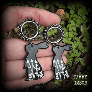 Featuring a black rabbit silhouette looking skyward with white floral sprig, these earrings weigh only 8 grams each and measure approx 6 from tip to tip. This pair has been made on 5/8” gauge (16mm) ornate surgical steel screw fit tunnels.