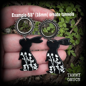 Featuring a black rabbit silhouette looking skyward with white floral sprig, these earrings weigh only 8 grams each and measure approx 6 from tip to tip. This pair has been made on 5/8” gauge (16mm) ornate surgical steel screw fit tunnels.