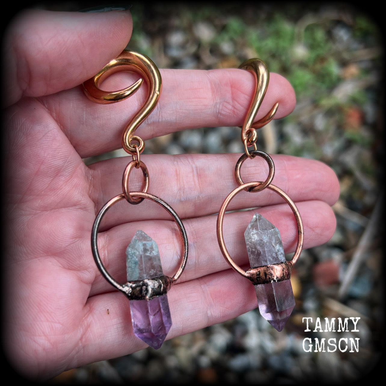Featuring a pair of beatifully rustic purple fluorite points in an antique copper setting, these gauged earrings measure just over 8cms from tip to tip, and weigh approx 13 grams each.
This pair has been made on 2 gauge (6mm) surgical steel full curl hooks, suitable for stretched lobes.