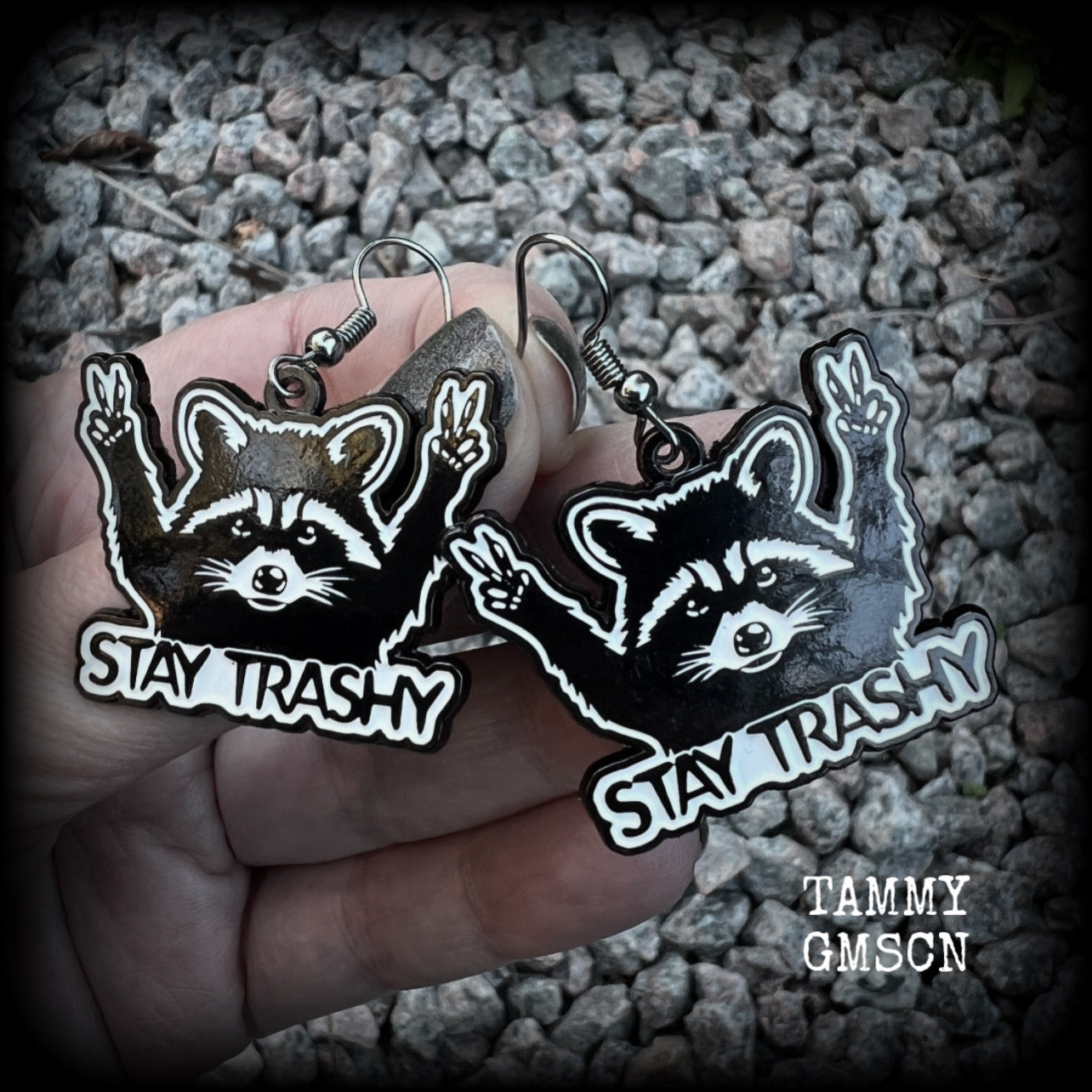These awesome ‘Stay trashy’ earrings feature a classic raccoon trash panda throwing up V for victory hand signs, measuring in at just under 5 cms from tip to tip and weighing approx 6 grams a piece.

This pair have been made with stainless steel french hooks, suitable for pierced ears.
