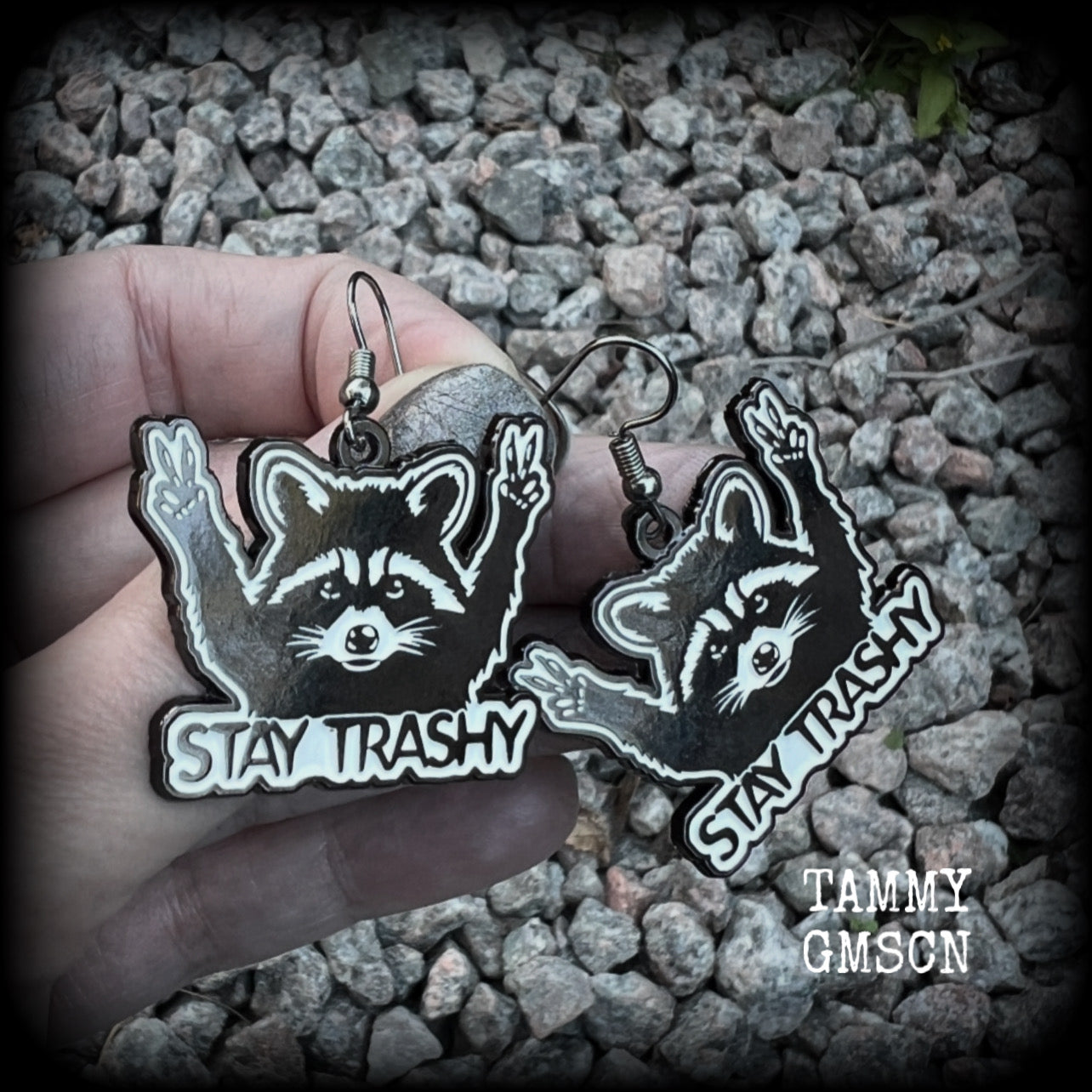 These awesome ‘Stay trashy’ earrings feature a classic raccoon trash panda throwing up V for victory hand signs, measuring in at just under 5 cms from tip to tip and weighing approx 6 grams a piece.

This pair have been made with stainless steel french hooks, suitable for pierced ears.