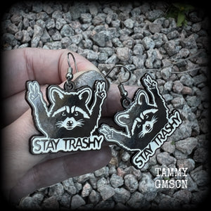 These awesome ‘Stay trashy’ earrings feature a classic raccoon trash panda throwing up V for victory hand signs, measuring in at just under 5 cms from tip to tip and weighing approx 6 grams a piece.

This pair have been made with stainless steel french hooks, suitable for pierced ears.