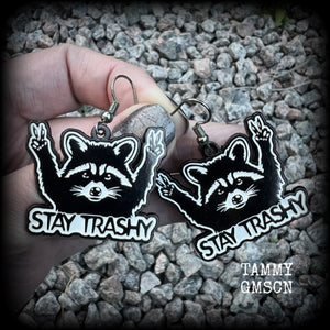 These awesome ‘Stay trashy’ earrings feature a classic raccoon trash panda throwing up V for victory hand signs, measuring in at just under 5 cms from tip to tip and weighing approx 6 grams a piece.

This pair have been made with stainless steel french hooks, suitable for pierced ears.
