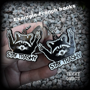 These awesome ‘Stay trashy’ earrings feature a classic raccoon trash panda throwing up V for victory hand signs, measuring in at just under 5 cms from tip to tip and weighing approx 6 grams a piece.

This pair have been made with stainless steel french hooks, suitable for pierced ears.