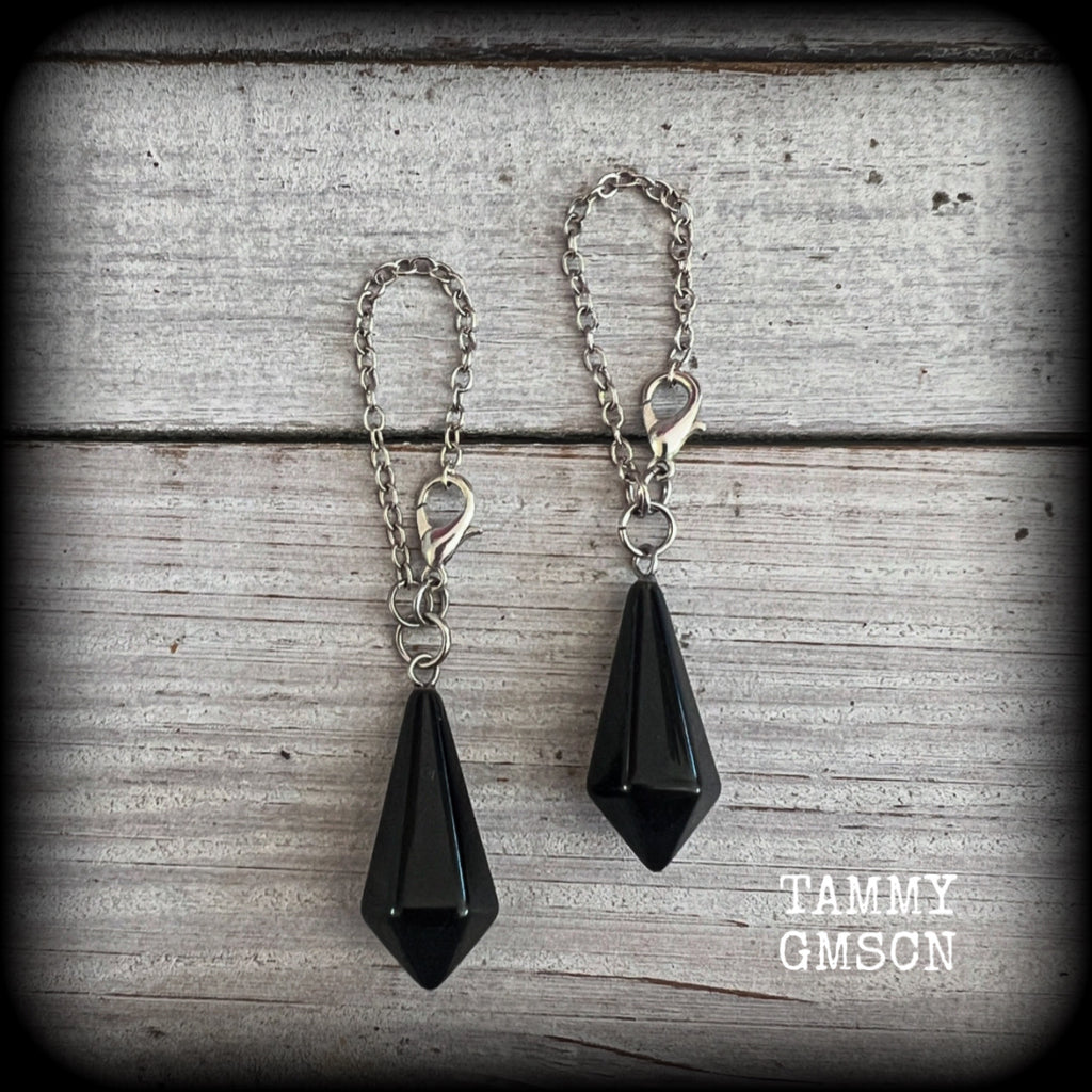 These gorgeous earrings have been made with pitch black obsidian divination pendulums, are nice and light weight at only 5 grams a piece, and are nice and dangly, measuring just over 7cms from tip to tip.

This pair has been made with our super versatile antique silver chain and lobster clasp 4mm option, to be worn through silicone earlets in stretched lobes from 6 gauge (4mm).
