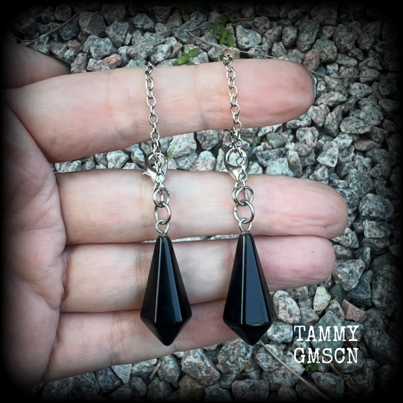 These gorgeous earrings have been made with pitch black obsidian divination pendulums, are nice and light weight at only 5 grams a piece, and are nice and dangly, measuring just over 7cms from tip to tip.

This pair has been made with our super versatile antique silver chain and lobster clasp 4mm option, to be worn through silicone earlets in stretched lobes from 6 gauge (4mm).