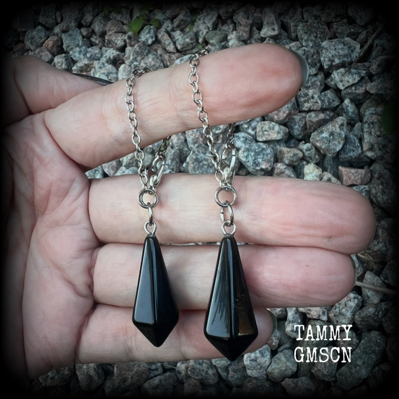 These gorgeous earrings have been made with pitch black obsidian divination pendulums, are nice and light weight at only 5 grams a piece, and are nice and dangly, measuring just over 7cms from tip to tip.

This pair has been made with our super versatile antique silver chain and lobster clasp 4mm option, to be worn through silicone earlets in stretched lobes from 6 gauge (4mm).