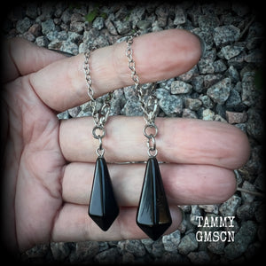 These gorgeous earrings have been made with pitch black obsidian divination pendulums, are nice and light weight at only 5 grams a piece, and are nice and dangly, measuring just over 7cms from tip to tip.

This pair has been made with our super versatile antique silver chain and lobster clasp 4mm option, to be worn through silicone earlets in stretched lobes from 6 gauge (4mm).