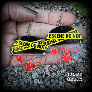 These awesome crime scene inspired earrings feature a bloodied hand print hanging beneath a cautionary crime scene sign, measuring approx 6.5cms from tip to tip and weighing only a few grams each.

This pair has been made with stainless steel french hooks, suitable for pierced ears.
