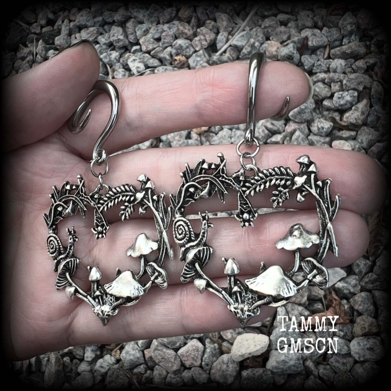 These awesome antique silver forest punk earrings are gorgeous!! 
Featuring a heart of ferns with snails, mushrooms and spiders, these earrings weigh approx 11 grams each, and measure in at just over 7cms from tip to tip.

This pair has been made on 6 gauge (4mm) gauge surgical steel full curls, to be worn in stretched lobes.