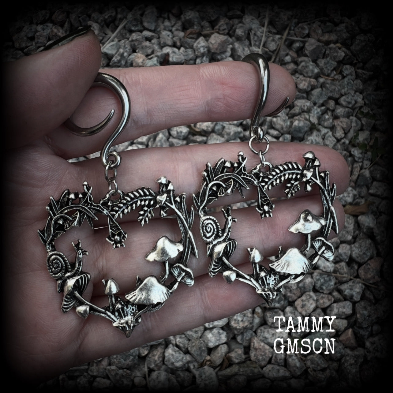 These awesome antique silver forest punk earrings are gorgeous!! 
Featuring a heart of ferns with snails, mushrooms and spiders, these earrings weigh approx 11 grams each, and measure in at just over 7cms from tip to tip.

This pair has been made on 6 gauge (4mm) gauge surgical steel full curls, to be worn in stretched lobes.