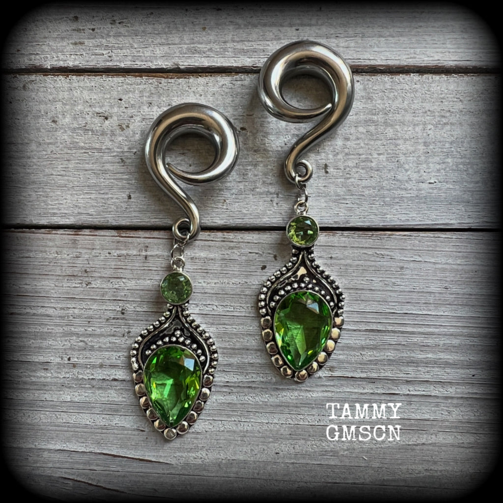 This pair of earrings features gorgeous green peridot gemstones in a boho antique silver setting, weighing approx 19 grams a piece and measuring just on 8.5cms from tip to tip.

This pair have been made on 0 gauge (8mm) surgical steel full curl hooks, to be worn in stretched lobes.