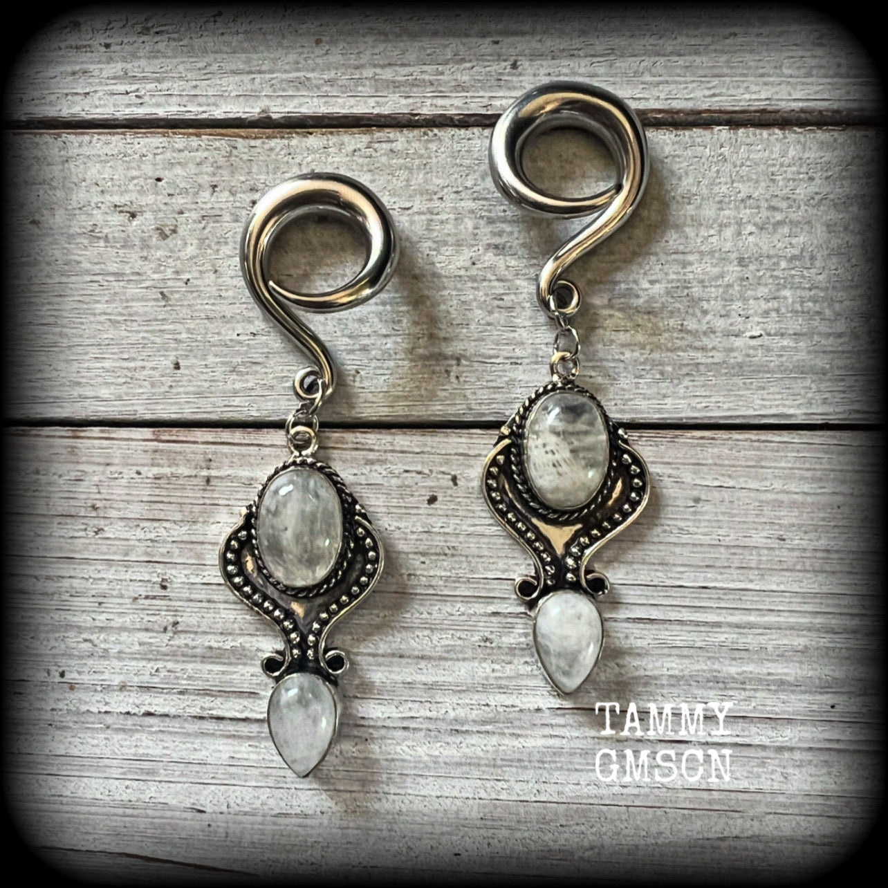 These gorgeous earrings feature polished Rainbow Moonstone gemstones in a beautiful boho antique silver setting, lovely and dangly at approx 8 cms from tip to tip, and not too heavy at 13 grams each.

This pair had been made on 2 gauge (6mm) surgical steel full curls, to be worn in stretched lobes.
