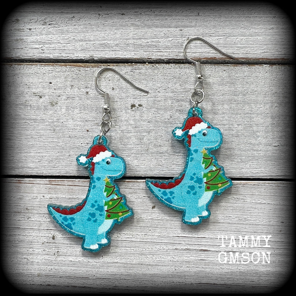 Featuring adorable festive Tyrannosaurus rex dinosaurs wearing Santa hats and holding Christmas trees, these awesome earrings are super lightweight, weighing only a few grams each and are nice and dangly, measuring just over 6 cms from tip to tip.

This pair of earrings has been made on stainless steel french hooks, suitable for pierced ears.