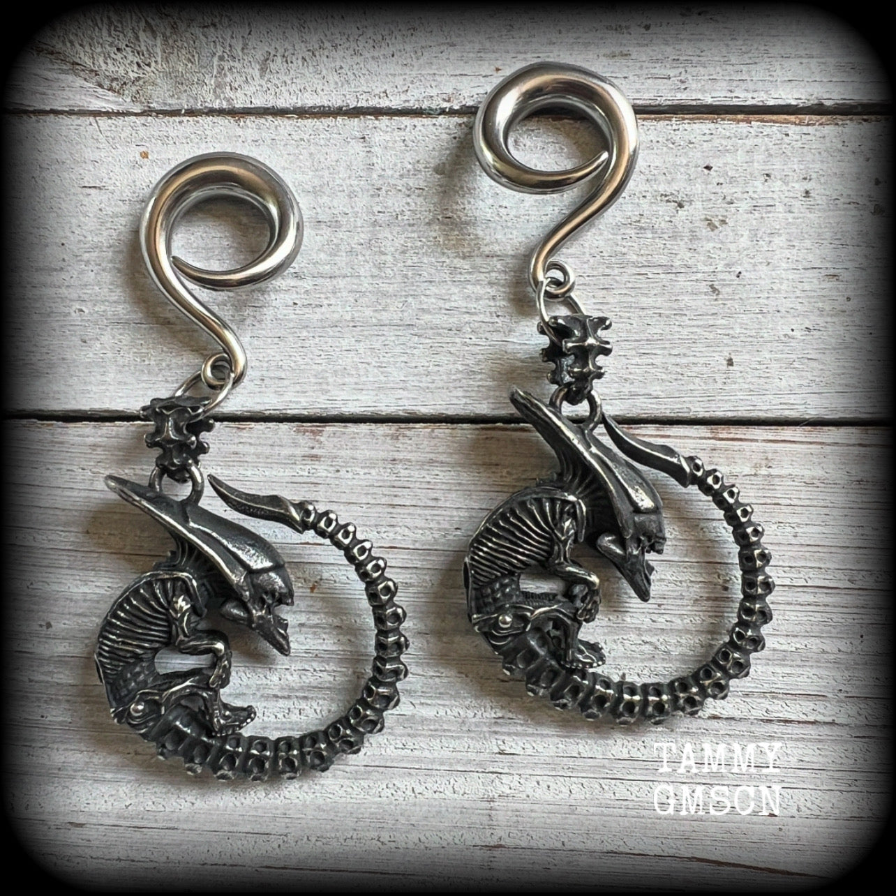 This pair of awesome ear hangers features a pair of gun metal grey antique silver Xenomorphs, weighing in at approx 28 grams a piece, and nice and dangly at 8cms from tip to tip. 

This pair has been made on 2 gauge (6mm) surgical steel full curl hooks, suitable for stretched lobes.
