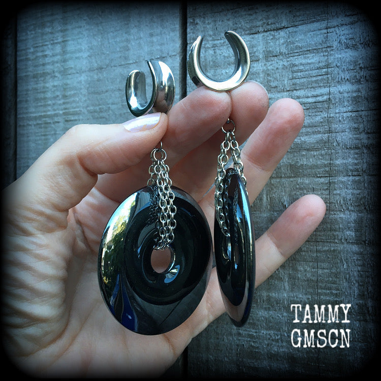 Hematite gauged earrings This is a pair of shiny black hematite donut gemstones with antique silver chain, weighing approx 50 grams a piece and measure just on 9cms from tip to tip.
This pair has been made on 5/8" gauge (16mm) surgical steel cradles,  for stretched lobes.