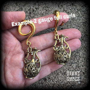 Inspired by the Star sign Aquarius-the water carrier, these gorgeous brass gauged earrings feature an ornate water jug, measuring 7 cms from tip to tip, and weighing approx 13 grams a piece.

This pair of earrings have been made on 2 gauge (6mm) surgical steel full curl hooks, suitable for stretched lobes.