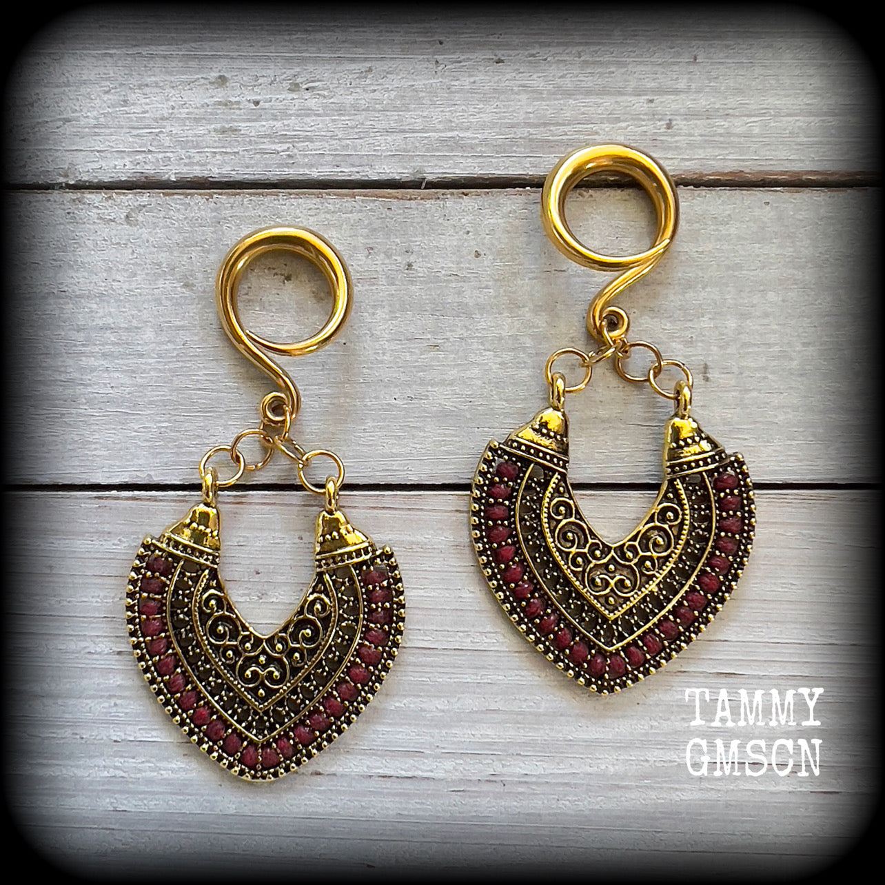 These striking earrings feature antique gold and red leather trim ornate charms, are nice and light weight, weighing approx 11 grams a piece, and measure just over 7cms from tip to tip.

This pair has been made with 6 gauge (4mm) gauge surgical steel full curl hooks, to be worn in stretched lobes.