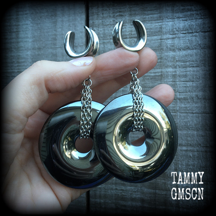 Gemstone ear weights This is a pair of shiny black hematite donut gemstones with antique silver chain, weighing approx 50 grams a piece and measure just on 9cms from tip to tip.
This pair has been made on 5/8" gauge (16mm) surgical steel cradles,  for stretched lobes.