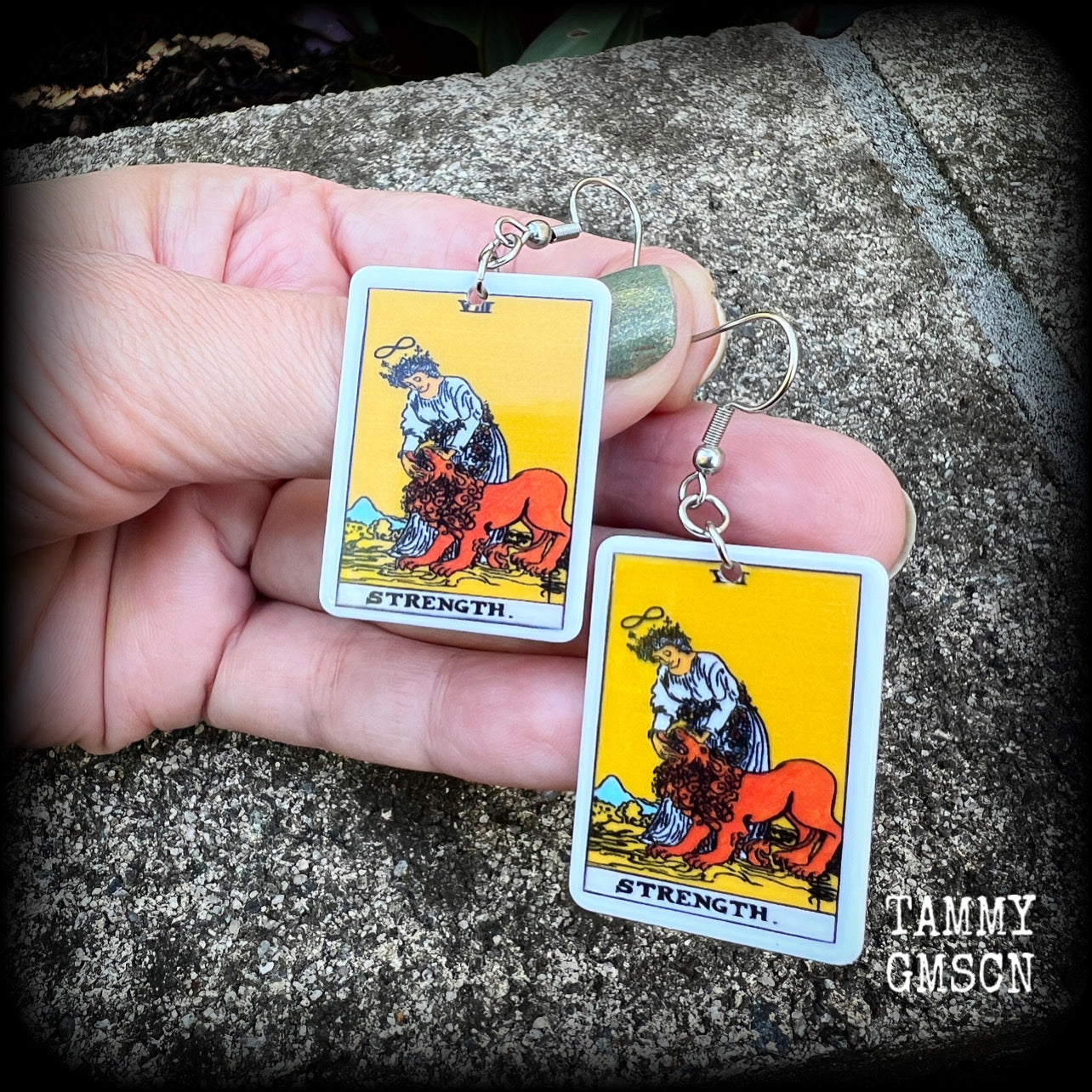 These classic Major Arcana earrings feature a lightweight plastic 'Strength' tarot card charm, measuring just under 6cms from tip to tip.

This pair has been made with stainless steel french hooks, suitable for pierced ears.