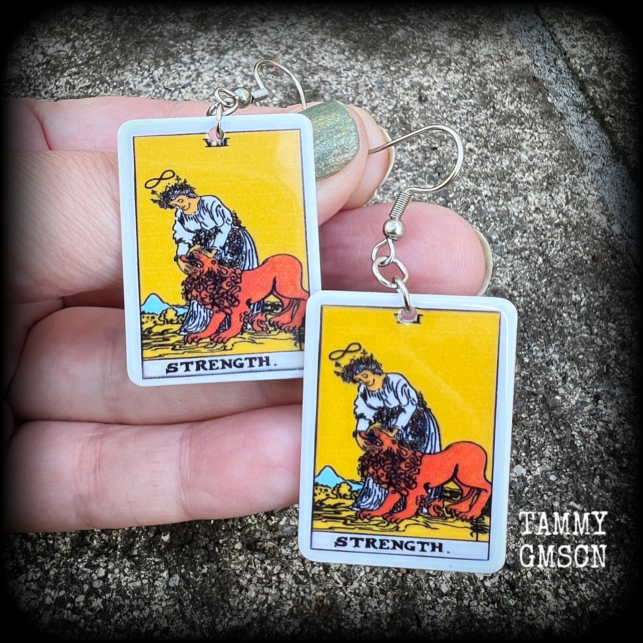 These classic Major Arcana earrings feature a lightweight plastic 'Strength' tarot card charm, measuring just under 6cms from tip to tip.

This pair has been made with stainless steel french hooks, suitable for pierced ears.