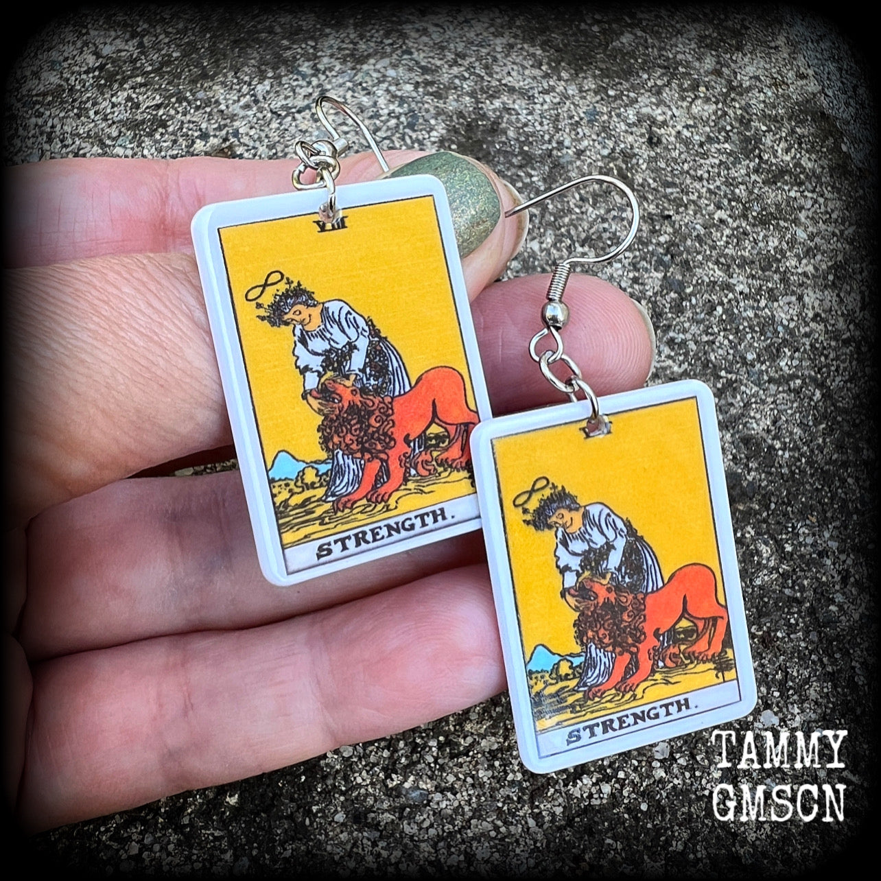 These classic Major Arcana earrings feature a lightweight plastic 'Strength' tarot card charm, measuring just under 6cms from tip to tip.

This pair has been made with stainless steel french hooks, suitable for pierced ears.