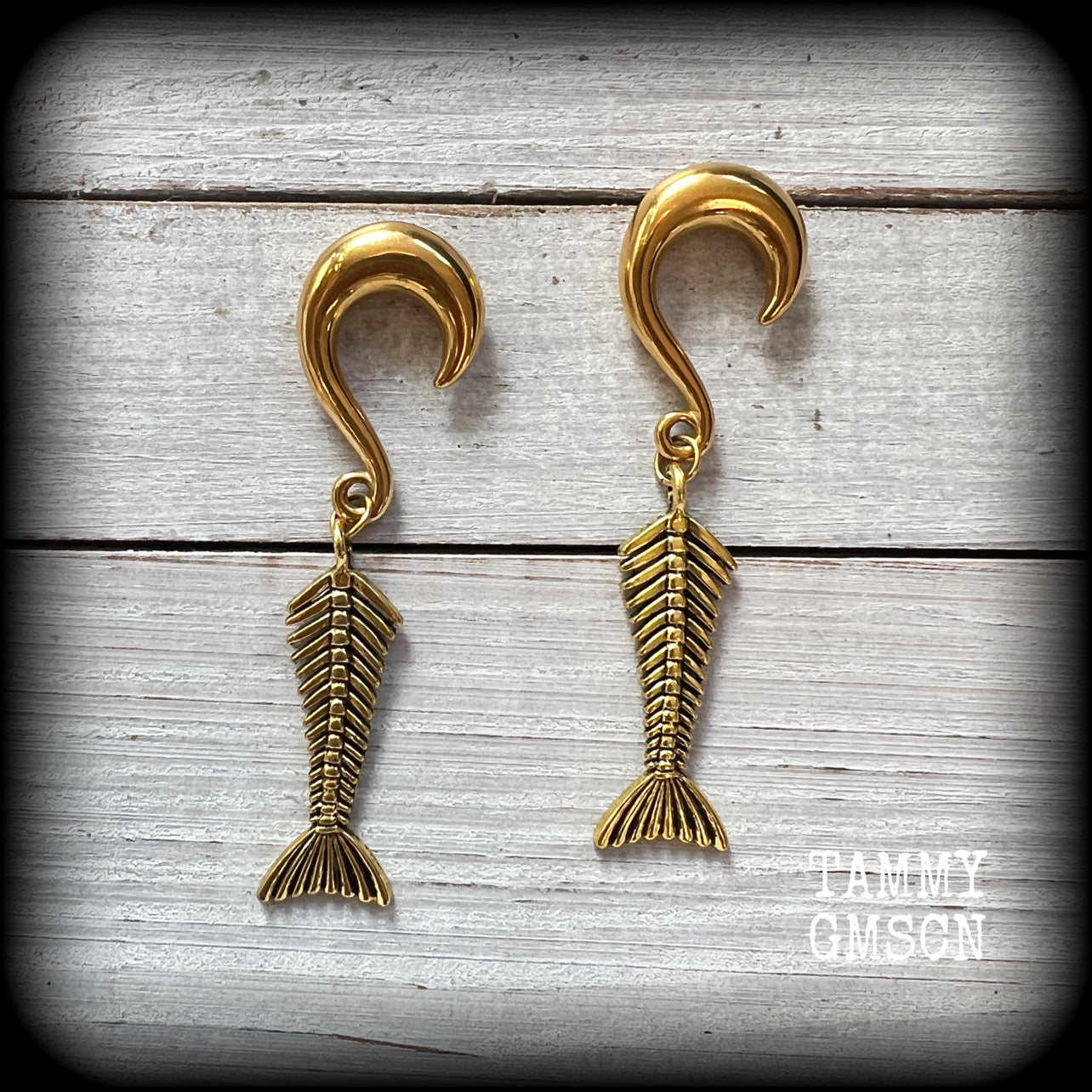This quirky pair of earrings features antique gold skeletal mermail tails are lovely and dangly, measuring just over 7cms from tip to tip, and are not too heavy at 12 grams each.

This pair have been made with 0 gauge (8mm) surgical steel half curl hooks, to be worn in stretched lobes.