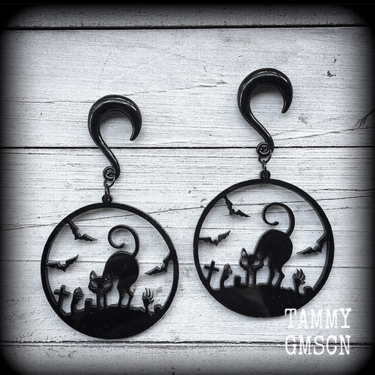 These super cute, super spooky black acrylic 'Zombie cat' gauged earrings feature a gorgeous black cat zombie cemetary scene complete with black bats and headstones!!

These are nice and dangly, measuring just under 9 cms from tip to tip and weighing approx 8 grams each, super light weight.

This pair has been made with 2 gauge (6mm) surgical steel half curl hooks, suitable for stretched lobes.