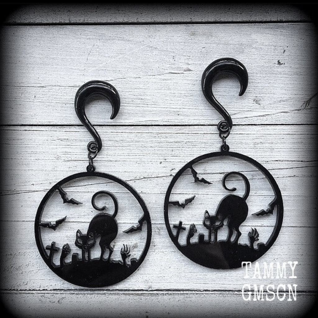 These super cute, super spooky black acrylic 'Zombie cat' gauged earrings feature a gorgeous black cat zombie cemetary scene complete with black bats and headstones!!

These are nice and dangly, measuring just under 9 cms from tip to tip and weighing approx 8 grams each, super light weight.

This pair has been made with 2 gauge (6mm) surgical steel half curl hooks, suitable for stretched lobes.