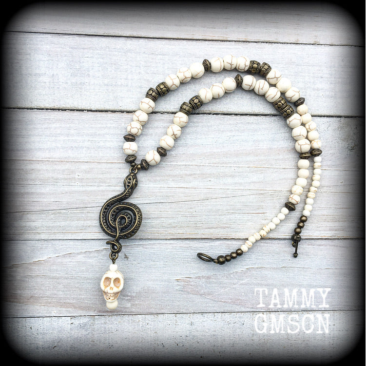 This unique necklace features a gorgeous antique bronze 'Ascending snake' with a large bone white howlite stone skull, on a strand of bone white stone beads dotted with ornate antique bronze beads.
This necklace measures 43cms from tip to tip when laid flat and fastens with an antique bronze toggle clasp.
